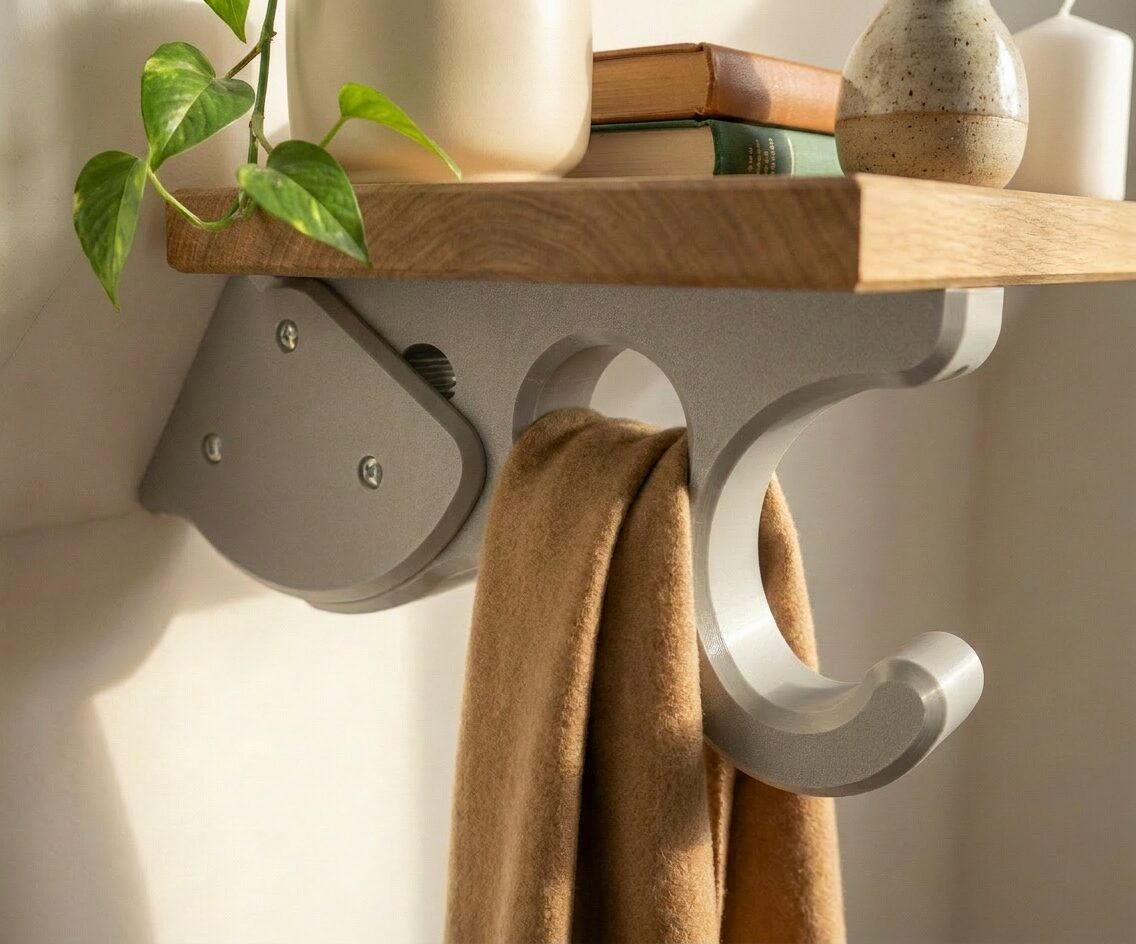 Oak shelf and hook bracket mounted under a sloped wall, holding books, a vase, and a folded blanket